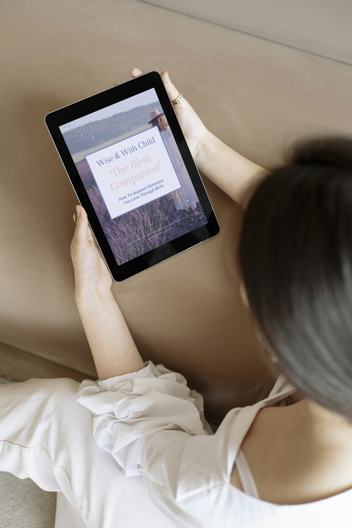 A woman reading The Intuitive Birth Guide & Planner on a tablet, showing how the downloadable guide can be used while preparing for birth.