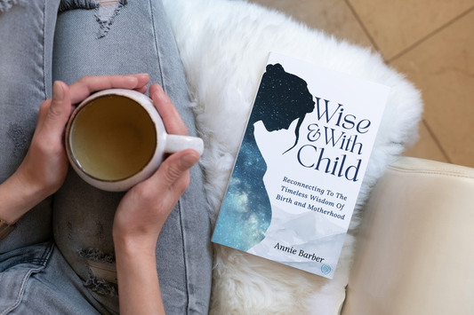 Wise & With Child pregnancy and birth book by Annie Barber beside a woman relaxing with a cup of tea.