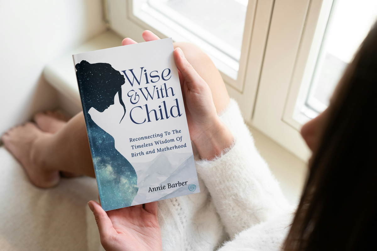 Pregnant woman holding Wise & With Child by Annie Barber, a thoughtful companion for pregnancy, birth and motherhood.